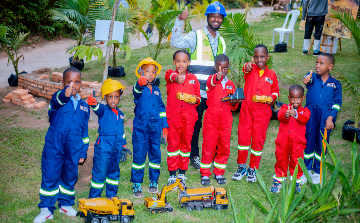 Philbert Dushimimana smiling with children wearing construction uniforms at the Ijabo Ryanjye talent project in Rwanda.