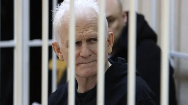 The image shows Nobel laureate Ales Bialiatski in a defendant's cage in Minsk, a key figure freed as Belarus freed prisoners after the US lifted sanctions.