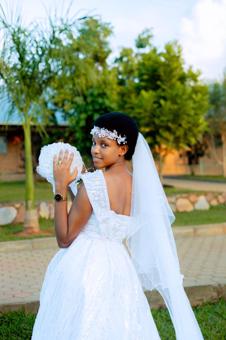 Donatha MUKESHIMANA smiling joyfully in a white wedding dress on her wedding day with Elie NSENGIMANA.