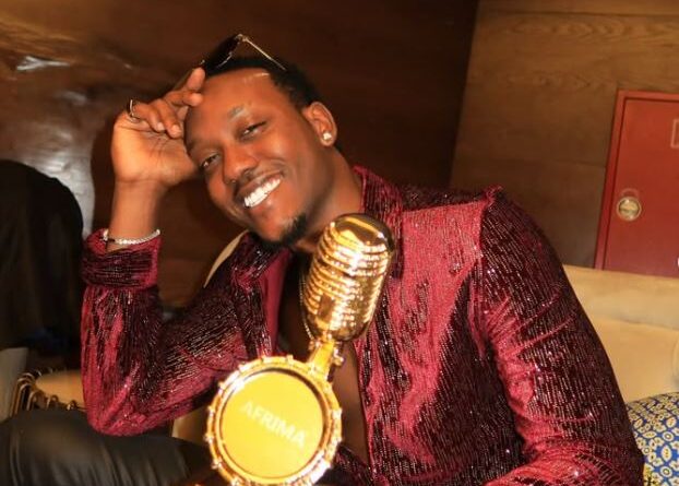 Rwandan music producer and artist ELEMENT smiling proudly while holding his AFRIMA 'Producer of the Year' award trophy.
