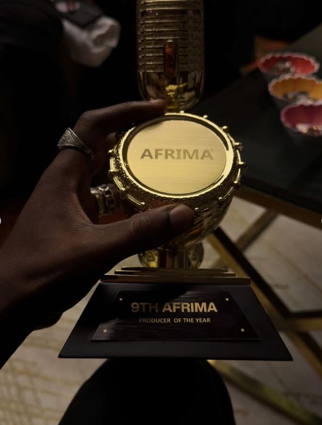 Close-up of the golden AFRIMA trophy with engraving that reads "9TH AFRIMA - PRODUCER OF THE YEAR" being held.
